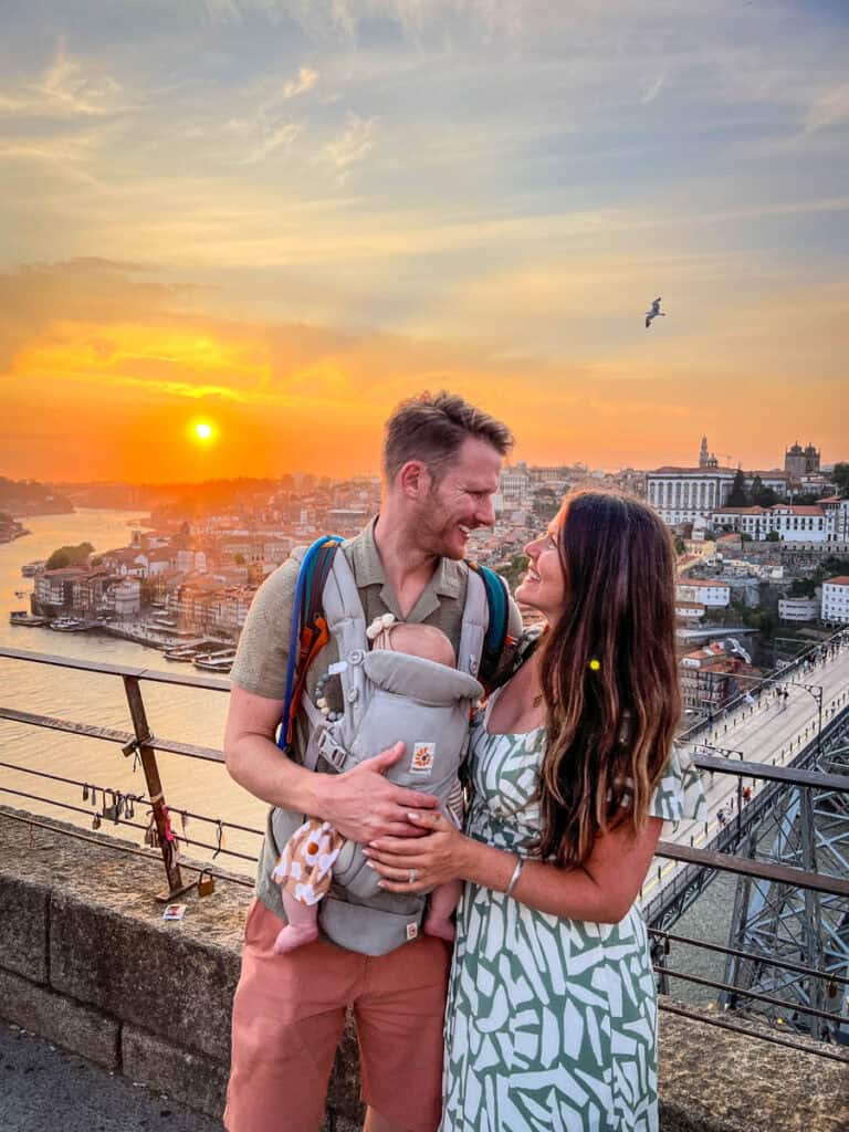 Family travel with baby, couple enjoying sunset in Porto Portugal, scenic city view at sunset from Dom Luís I Bridge, maternity photography lifestyle, travel photography adventure, cityscape.